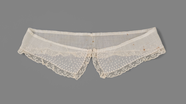 Ein Paar weiße Spitzenhöschen mit zarter Spitzenborte auf einem grauen Hintergrund.