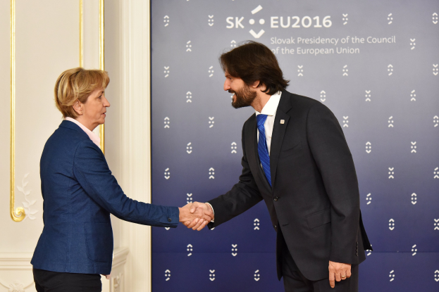 Bundeskanzlerin Angela Merkel und Bundespräsident Joachim Gauck schütteln sich vor einer Wand mit einem "EU-Gipfel"-Banner und einer Tür im Hintergrund die Hände, beide lächeln.