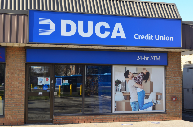 Außenansicht eines gläsernen Gebäudes mit der Aufschrift "Duca Credit Union" und einem Himmel als Hintergrund.