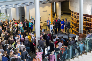 Gruppe von Menschen auf einer Treppe, die zu einem Podium mit Mikrofon führt, vor einem Publikum mit Kameras auf der 2018 Nationalen Frauen-Gesundheitskonferenz.