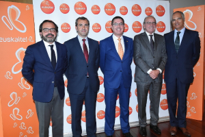 Eine Gruppe von M√§nnern, die f√ľr ein Foto posieren, mit Bannern im Hintergrund, die den Namen einer Organisation tragen.