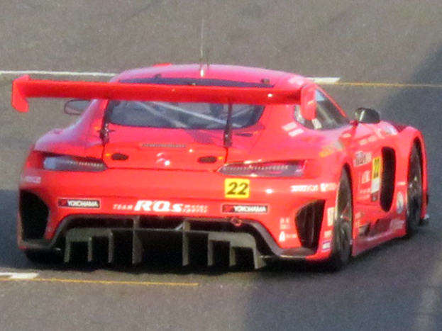 Roter Porsche 911 GTS Rennwagen auf einer Rennstrecke mit großem Heckspoiler und Flügel, niedriger Profil, breiter Stand und schwarzen Rädern.