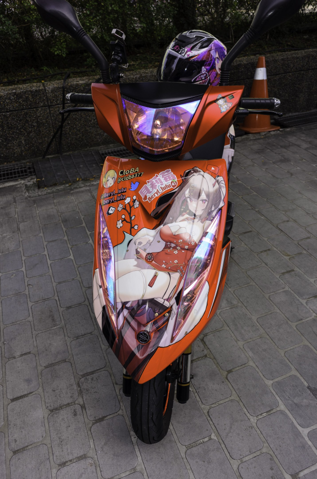 Ein oranges E-Scooter auf einer Straße geparkt mit einem Helm daneben, neben einer Verkehrsinsel, einer Wand und Bäumen.