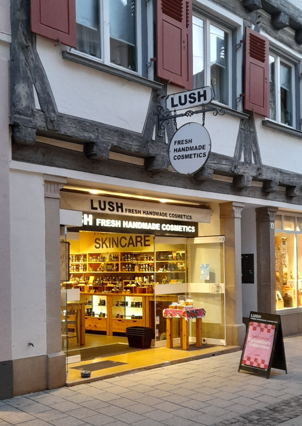 Storefront of "Lush Skincare" with interior furniture including cabinetry, a desk, and a chair visible through the window.