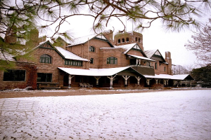 Ein Gebäude mit Fenstern, Säulen und Stühlen, mit einer Bank und einem Zweig auf der rechten Seite.