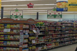 Ein Supermarktinneres mit sichtbaren Lebensmitteln, Deckenbeleuchtung und Schildern.