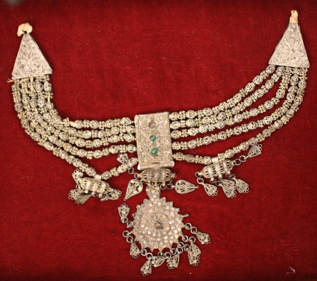 Silberne Kette mit Smaragden und Diamanten auf rotem Samt.