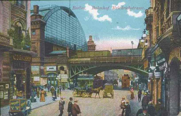 Eine alte Postkarte zeigt eine belebte Straßen Szenerie in Berlin, Deutschland, mit Menschen, Pferdefuhrwerken, Gebäuden, Laternenpfählen, einer Brücke und einem bewölkten Himmel, mit Text oben.