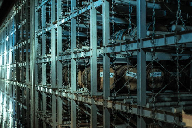 Ein großes Lager mit zahlreichen Fässern, die ordentlich in einem Gestell gestapelt und mit Metallstangen und Ketten verbunden sind.