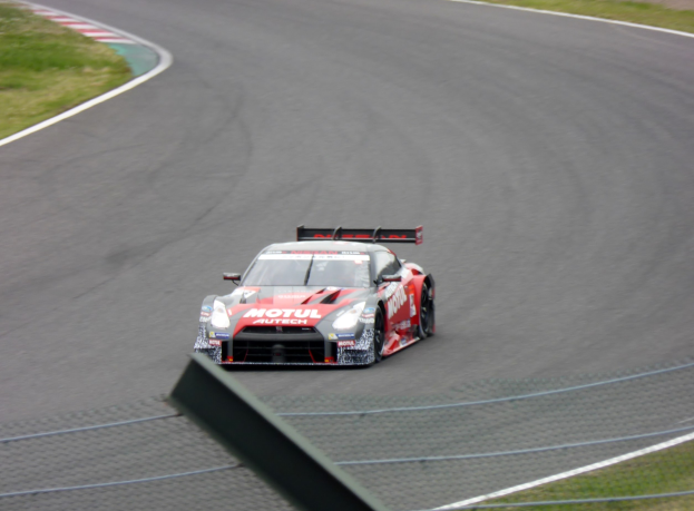 Ein Nissan GT-R Nismo GT3 Rennauto auf der Nürburgring 24 Stunden Strecke mit grünem Gras auf beiden Seiten.