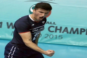 Ein Mann in einem blauen Hemd und schwarzen Shorts spielt Handball mit einem Banner "Kabaddi World Cup 2015" im Hintergrund.