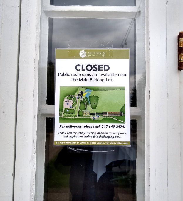 Glasstür mit einem Plakat, auf dem "Geschlossene öffentliche Toiletten in der Nähe des Hauptparkplatzes" steht und ein unklares Objekt auf der rechten Seite.