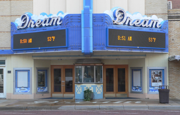 Außenansicht des Dream Theaters in St. Louis, Missouri, mit Glastüren und -fenstern, einem Namensschild, einem Müllbehälter, einem Topf mit einer Pflanze und einer Straße im Vordergrund.