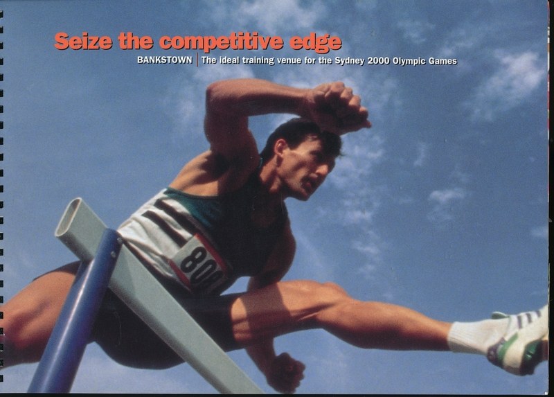 Ein Mann in einem hellgelben Overall und blauen Shorts springt über ein Hindernis gegen einen hellblauen Himmel mit weißen Wolken, wobei die Wörter "Seize the Competitive Edge" auf einem Buchumschlag im Hintergrund sichtbar sind.