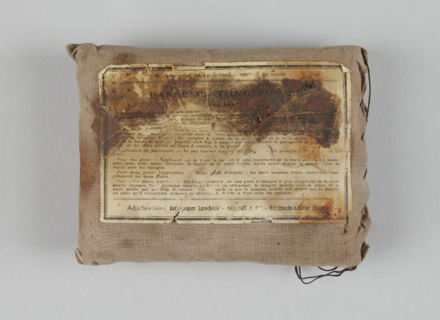 Kleiner Verbandskasten mit einem informativen Blatt obenauf.